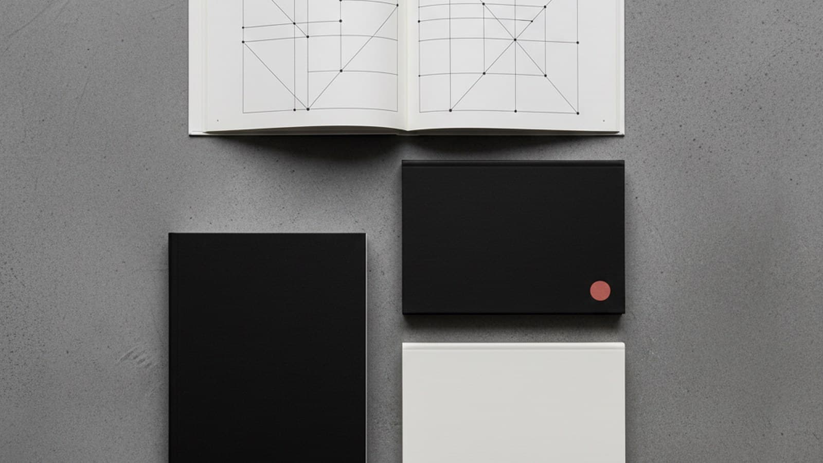 Cuatro manuales contemporáneos editoriales — Mailchimp Stripe Press Slack Oatly desplegados sobre mesa de estudio editorial concreto